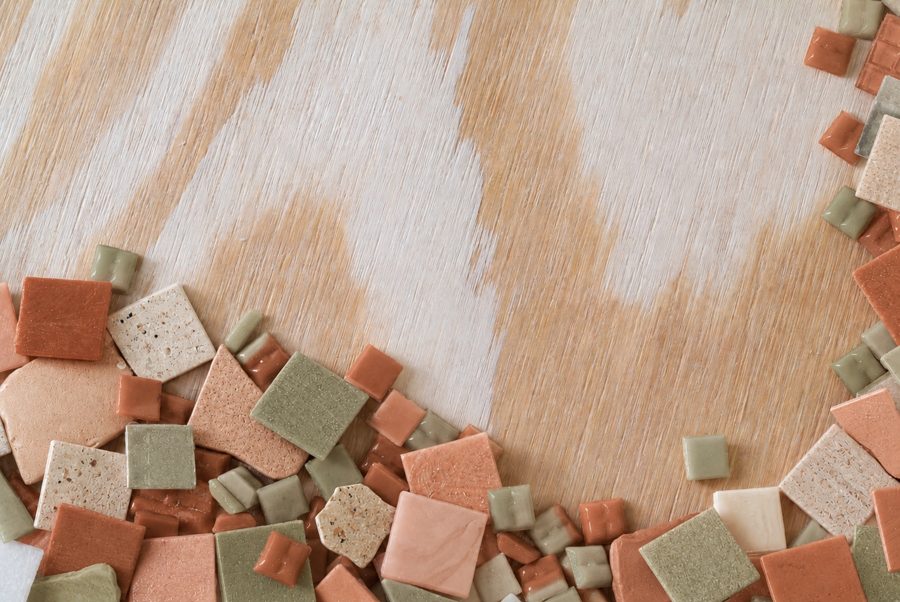Colorful mosaic tiles arranged on a wood surface